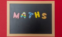 Black chalkboard with wooden frame, word, text maths in colorful letters, red wall background